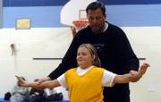 Former Kansas University basketball player Mike Maddox shows his daughter, Jamie, 10, how to position herself during her basketball practice Wednesday night at Deerfield School. Ninety-five percent of the coaches in Lawrences recreation league are parents, says Lee Ice, youth sports director for Parks and Rec. 